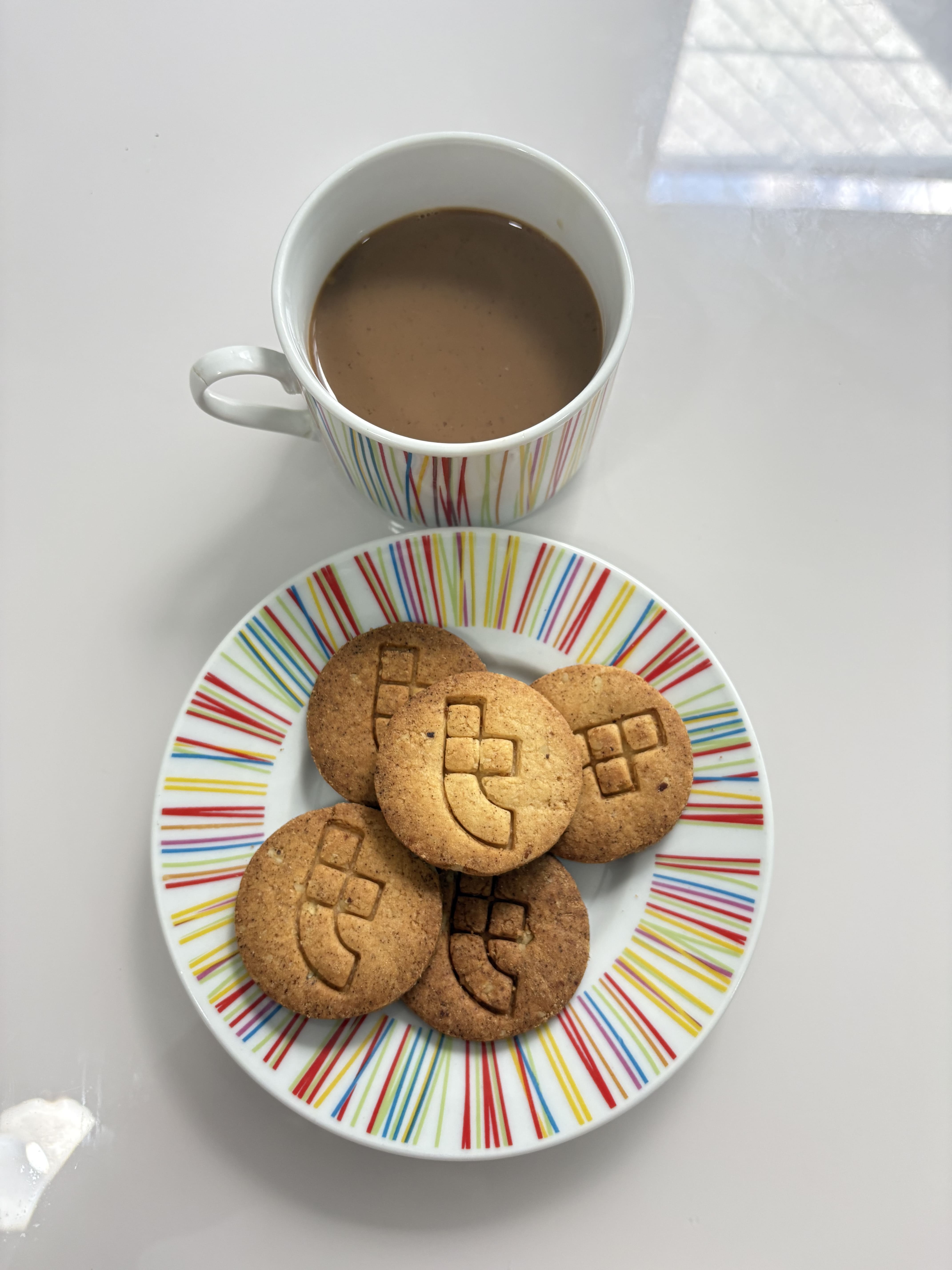 Uma xícara de café sofisticada acompanhada de biscoitos personalizados com a logo da Toglab.