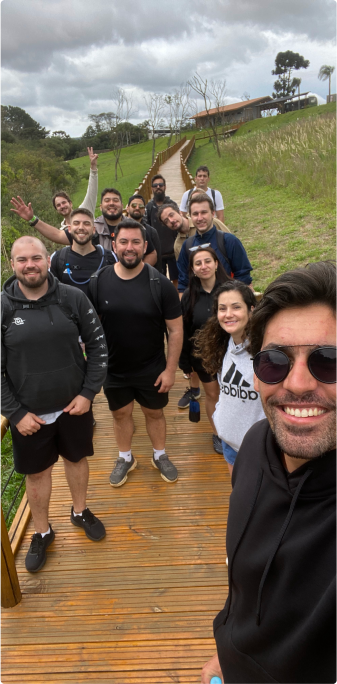 Group of people on an outdoor trail. A group of people posing for a photo on a wooden trail outdoors. The group is smiling and seems to be enjoying a hike on a cloudy day.