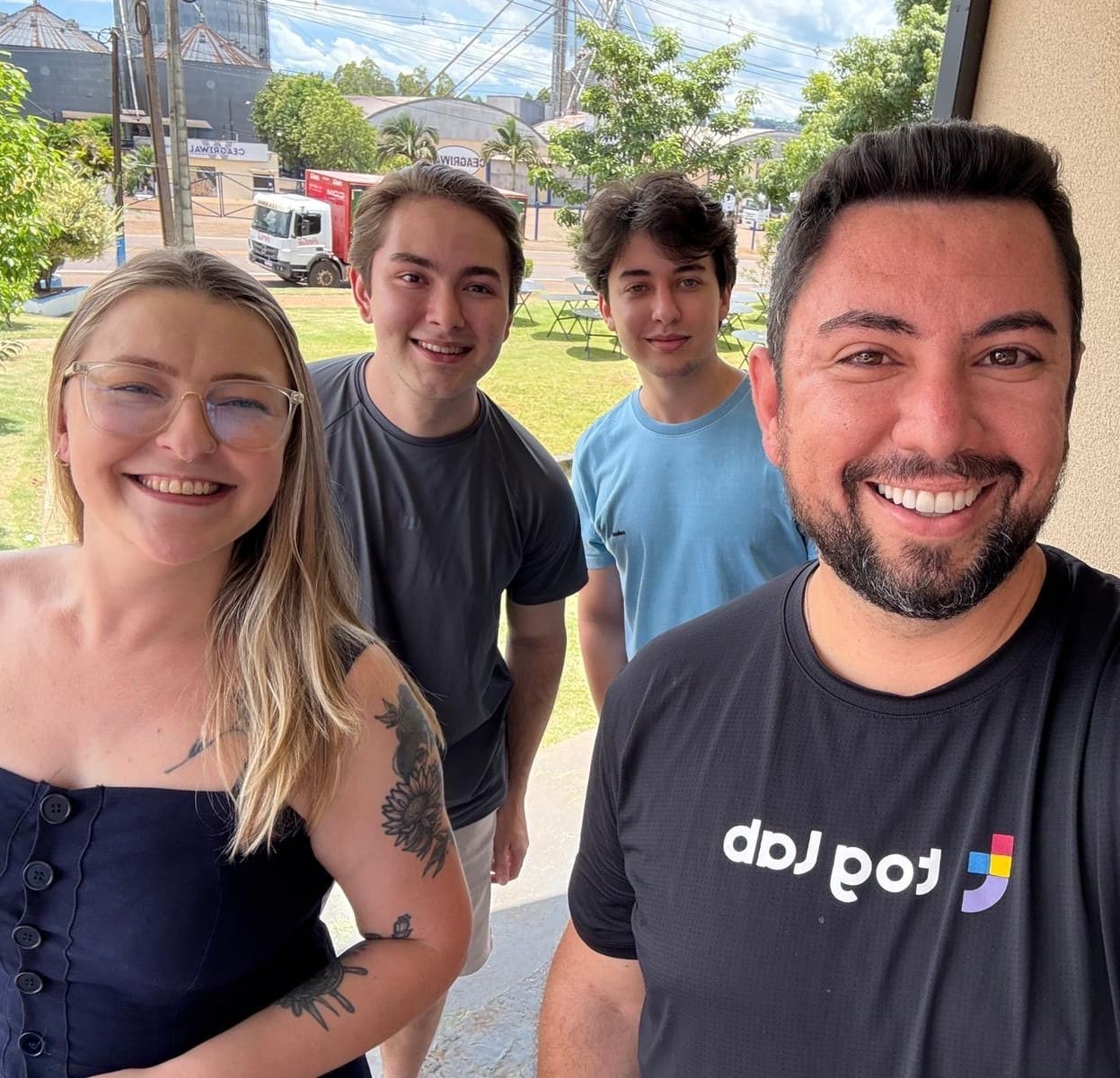 Quatro pessoas sorrindo em uma selfie ao ar livre, representando o time Toglab em um ambiente descontraído.