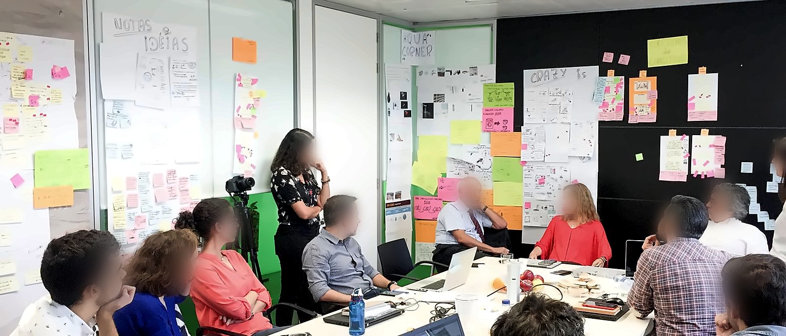 Team di ADENE e facilitatori in una sala con le pareti coperte di post-it, schizzi e idee del design sprint