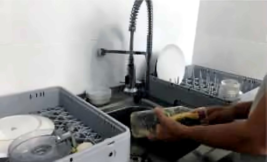 Mani che lavano i piatti in un lavello durante l’osservazione sul campo