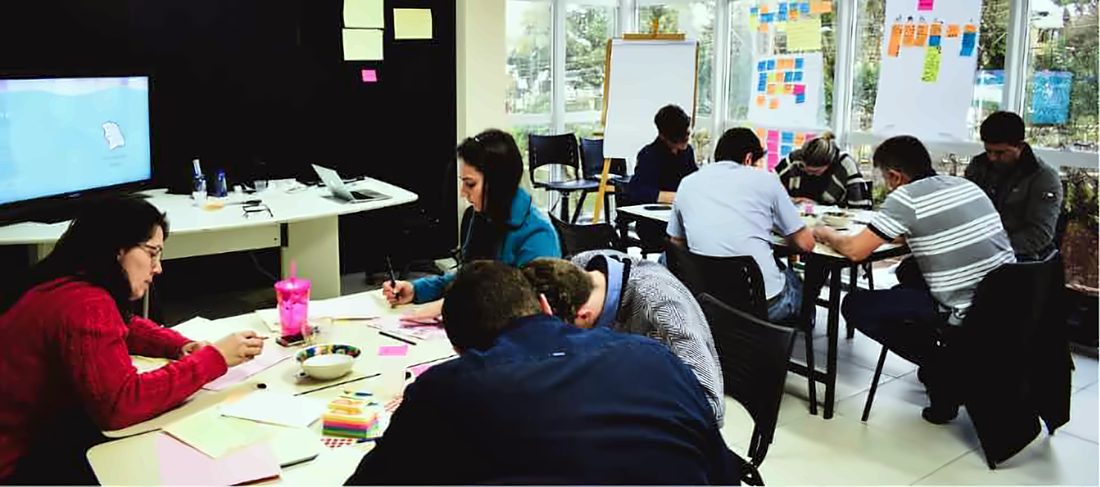 Persone che lavorano in gruppi sedute ai tavoli durante il design sprint