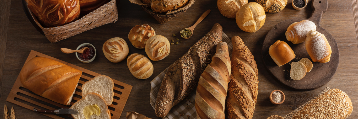 Various breads and baked goods arranged on a wooden table. The image represents the variety of products offered by Grupo Doce Doce.