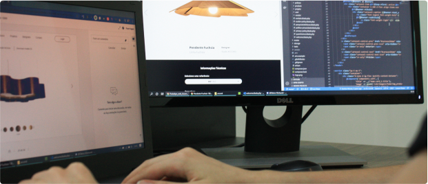 Developing a product design website with programming code. Person working on a laptop and monitor. The right monitor displays programming code, while the laptop on the left shows a product design website with a light fixture.